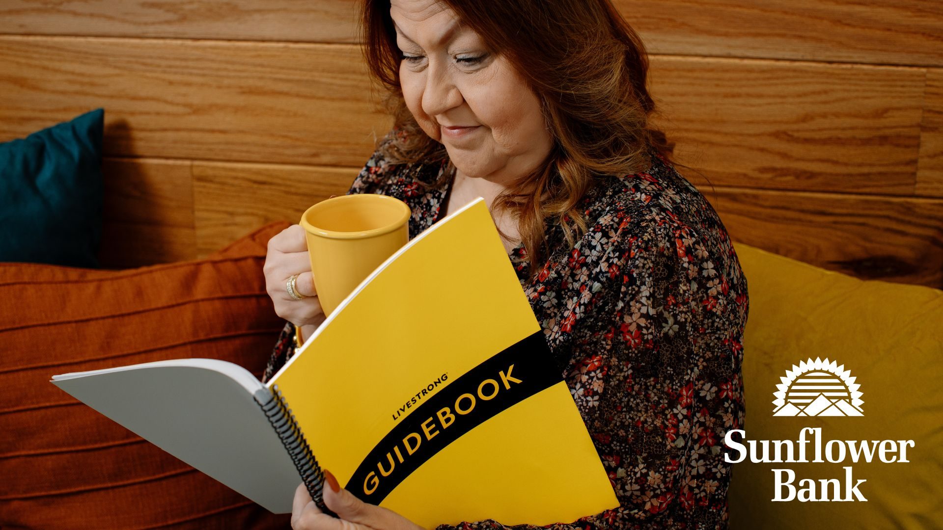 A woman reading a magazine and drinking from a mug