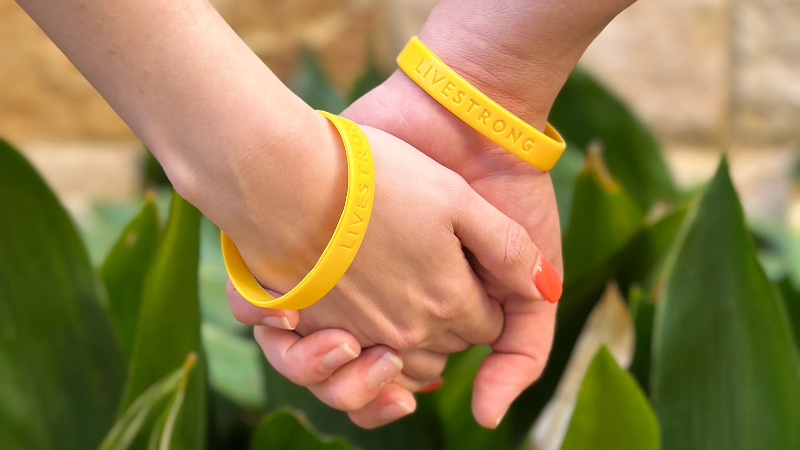 Two people holding hands wearing yellow wristbands