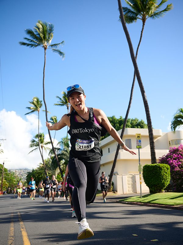 Young woman running with palm trees in background