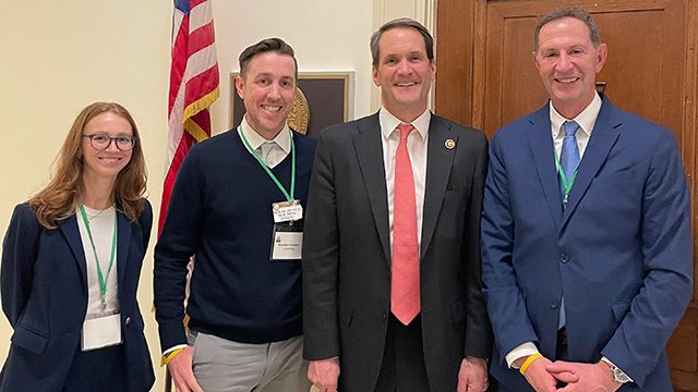 Cuatro profesionales de pie frente a una bandera estadounidense.