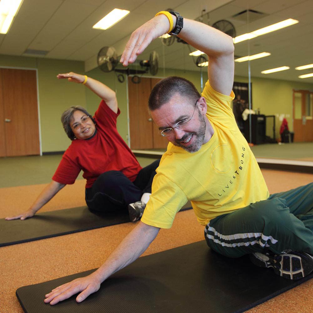 Dos personas estirándose sobre esterillas de yoga.