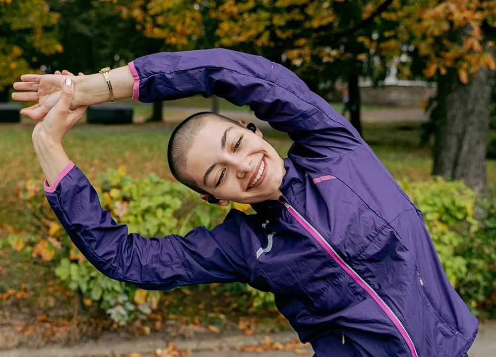 Young woman with short hair stretching outdoors