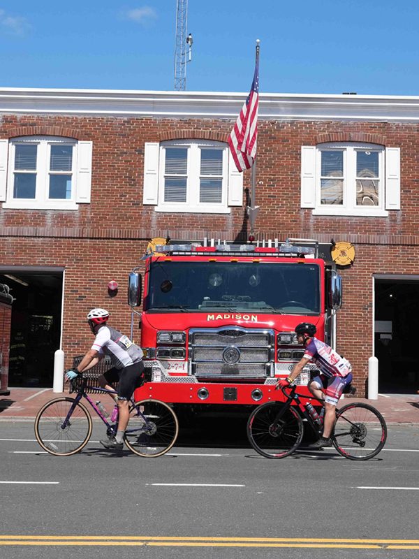 2 people cycling in front of a fire truck