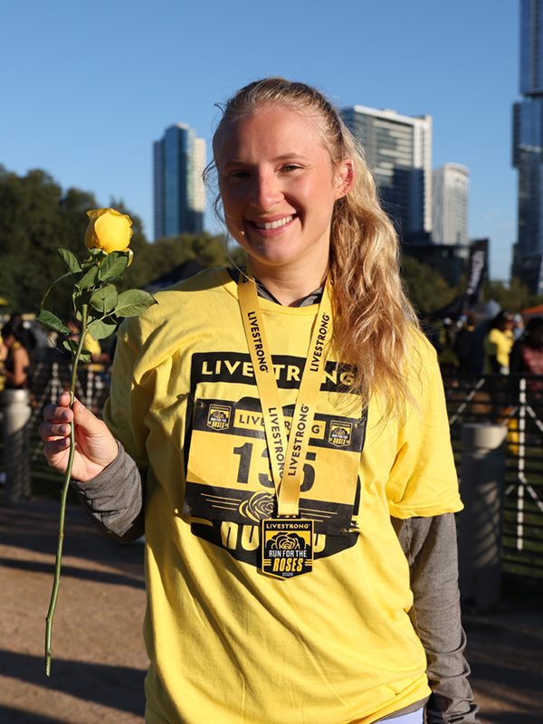 Young woman wearing medal holding yellow rose after a run